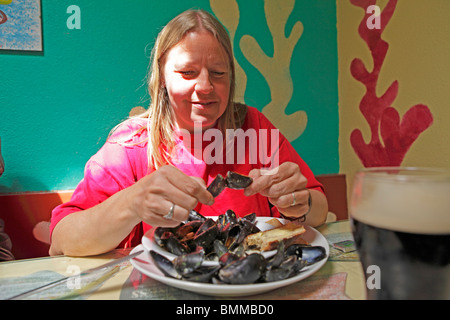 Porträt einer jungen Frau Essen Muscheln in einem Restaurant, Dingle, County Kerry, Irland Stockfoto