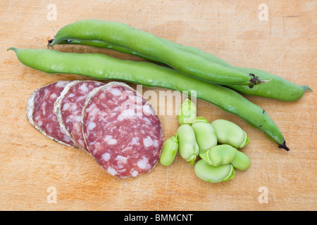 Drei Salami-Scheiben mit Bohnen auf einem Holz Schneidebrett Stockfoto