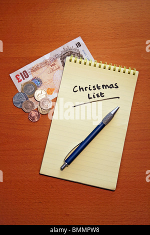 Christmas Shopping List auf farbigen Spirale gebunden Pad mit Geld: Metapher; Knapp bei Kasse Stockfoto