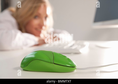 Grüne Maus auf Büro-Desktop mit Frau Stockfoto