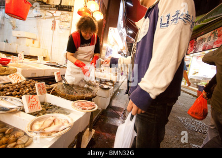Einpacken und Zahlen für Fisch und Meeresfrüchte zu einem lokalen Fischmarkt in Wan Chai, Hong Kong Stockfoto