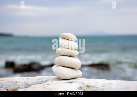 Stapel von ausgewogenen Steinen auf Felsen mit Meer im Hintergrund Stockfoto
