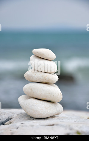Stapel von ausgewogenen Steinen auf Felsen mit Meer im Hintergrund Stockfoto