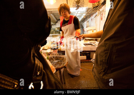 Einpacken und Zahlen für Fisch und Meeresfrüchte zu einem lokalen Fischmarkt in Wan Chai, Hong Kong Stockfoto