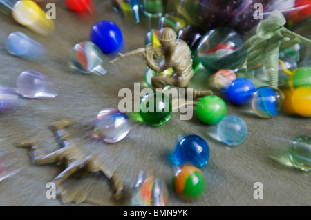 Ein Kampf findet mit grünen Kunststoff Aktion Figur Spielzeugsoldaten und Marmor. Stockfoto