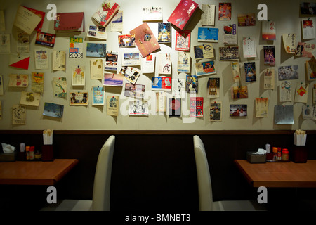 Postkarten an der Wand einer japanischen Noodle Bar versteckt unterhalb der Straße in Kowloon von Reisenden auf der ganzen Welt, Hong Kong. Stockfoto