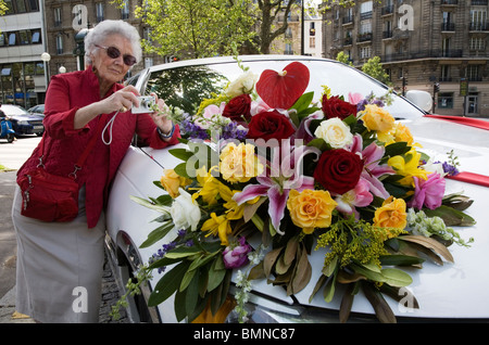 Eine alte Dame fotografieren Hochzeitsauto mit einem Blumenstrauß in Paris Stockfoto