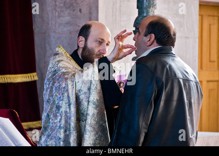 Priester taufte einen erwachsenen Mann in einer orthodoxen Kirche in Armenien. Stockfoto
