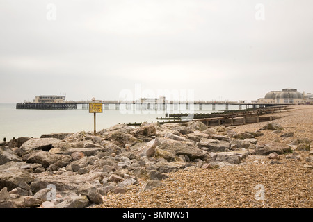 Eine Möwe auf einem Schild am Strand sitzt und schaut in Richtung Pier in Worthing in West Sussex, England. Stockfoto