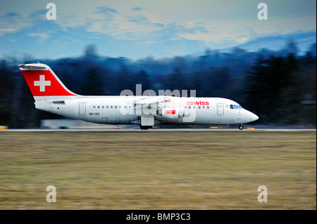 Eine Avro RJ100 abheben vom Genfer Flughafen entfernt an einem Winterabend, Bewegungsunschärfe auf den Hintergrund. Stockfoto