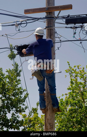 Elektriker arbeiten hoch oben auf einem Strommast Stockfoto