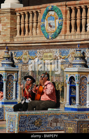 Straßenmusikanten sitzen auf einer gefliesten Bank in der Plaza de Espana, Sevilla, Provinz Sevilla, Andalusien, Spanien, Westeuropa. Stockfoto