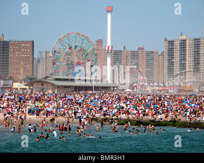 Eine Urlaub-Menge von mehr als 1 Million sonnt sich und schwimmt am Strand der berühmten Vergnügungspark Coney Island in Brooklyn, NYC Stockfoto