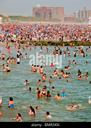 Eine Urlaub-Menge von mehr als 1 Million sonnt sich und schwimmt am Strand der berühmten Vergnügungspark Coney Island in Brooklyn, NYC Stockfoto