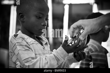 Mann er Süßigkeiten für ein Swahili-Kind in Tansania Stockfoto