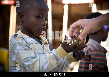 Mann er Süßigkeiten für ein Swahili-Kind in Tansania Stockfoto