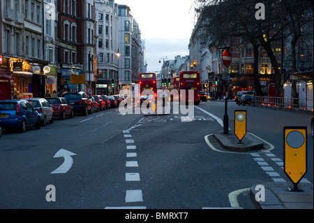 Berühmten roten Londoner Busse fahren entlang der Strand in Richtung Trafalgar Square in der Abenddämmerung. Stockfoto