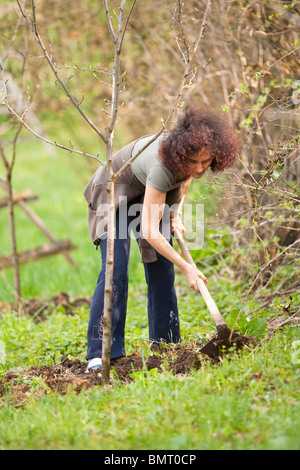 Junge rothaarige Dame arbeitet mit einer Hacke auf dem Lande Stockfoto