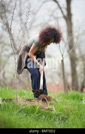 Junge rothaarige Dame arbeitet mit einer Hacke auf dem Lande Stockfoto