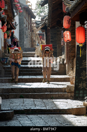 Mann und Frau tragen Lasten Altstadt Lijiang Yunnan China Stockfoto