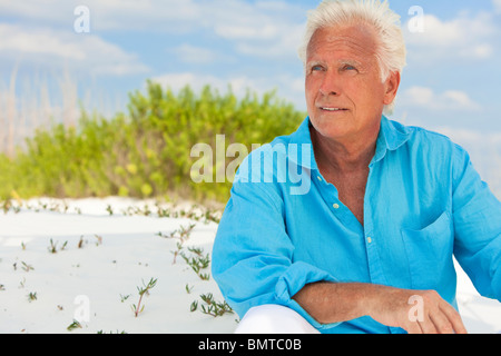 Porträt eines glücklichen attraktive schön senior sitzen nach unten außen an einem weißen Sandstrand Stockfoto