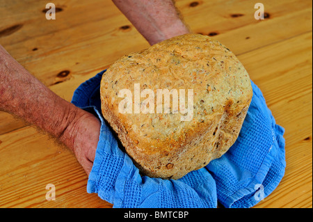 Ein Bäcker hält sich frisch gebackenes Brot Stockfoto