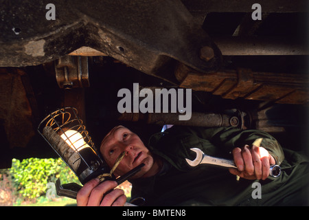 Mechaniker arbeiten unter Fahrzeug mit Schraubenschlüssel und Inspektion Lampe Stockfoto