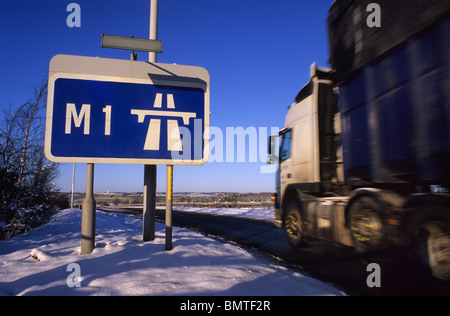 artikuliert LKW vorbei Roadsign Angabe Beginn der Autobahn M1 im Winterschnee in der Nähe von Leeds Yorkshire UK Stockfoto