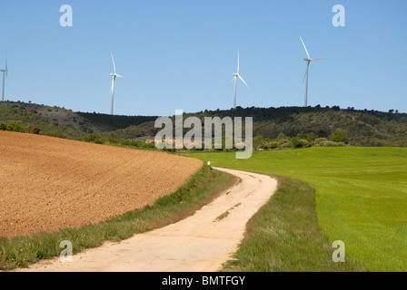 Landstraße durch Weizen Felder Windkraftwerke auf dem Horizont, in der Nähe von Huete, Cuenca Provinz Kastilien-La Mancha, Spanien Stockfoto