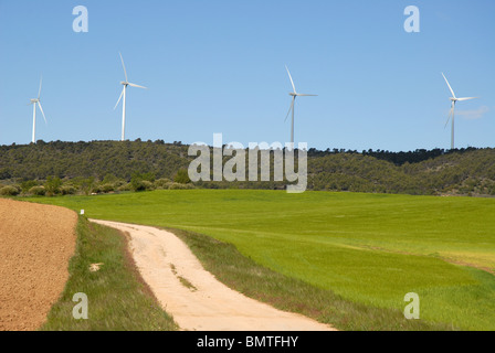 ländliche Strecke durch Weizen Felder Windkraftwerke auf dem Horizont, in der Nähe von Huete, Cuenca Provinz Kastilien-La Mancha, Spanien Stockfoto