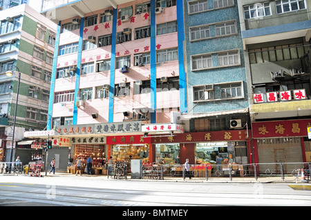 6 chinesische Straße Niveau getrocknet Essen und Medizin Geschäfte unter einem sonnigen, rosa, blau Wohnung Block, Des Voeux Road West, Hongkong Stockfoto