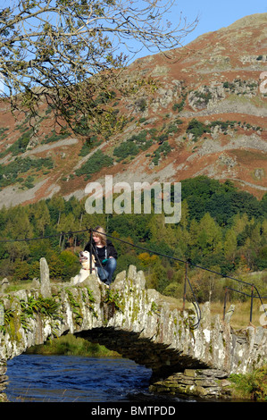 Walker und Hund über Slater Brücke über den Fluß Brathay in kleinen Langdale Stockfoto