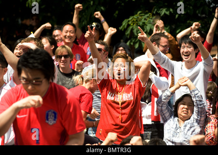 Südkoreanischen Fußball-Fans feiern ein Ziel auf einer großen Leinwand in einem Londoner Pub Garten während der WM 2010 Stockfoto