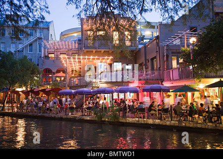 Menschen, die Essen an Tischen im Schatten in der Dämmerung am San Antonio River Walk Texas USA Stockfoto