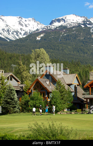 Eine Gruppe von Golfern spielen Sie eine Runde im Nicklaus North Golf Club unter einem verschneiten Berggipfel. Whistler, BC, Kanada Stockfoto