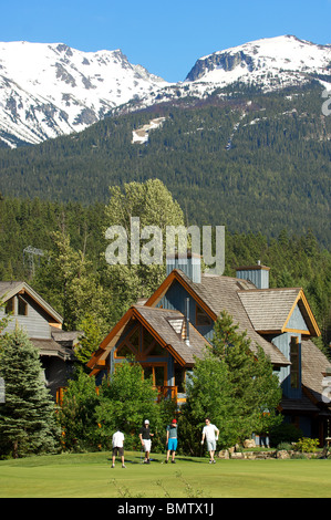 Eine Gruppe von Golfern spielen Sie eine Runde im Nicklaus North Golf Club unter einem verschneiten Berggipfel. Whistler, BC, Kanada Stockfoto