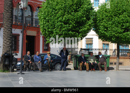 Ältere spanische Männer sitzen auf den Bänken in der Plaza de San Fernando, Carmona, Provinz Sevilla, Andalusien, Spanien, Europa. Stockfoto