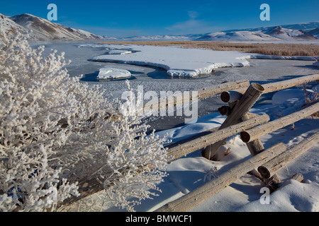 Jackson Hole, WY Winter Morgenlicht auf der mattierten Zaunleitung über einen gefrorenen Flat Creek in das National Elk Refuge Stockfoto