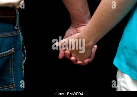 Nahaufnahme von Mann und Frau, die Hand in Hand gegen einen schwarzen Hintergrund. Konzept, Liebe, Romantik, Zärtlichkeit. Konzeptionelle. Stockfoto