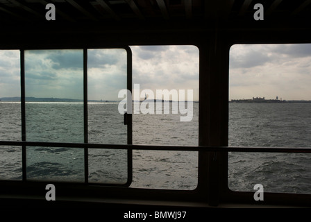 Freiheitsstatue Ellis Island New York USA schoss durch das Fenster einer Fähre auf dem Hudson River Stockfoto