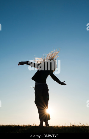 Young Girl energetisch, Spaß haben und tanzen um bei Sonnenuntergang. Silhouette Stockfoto
