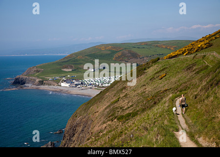 Mann zu Fuß Hund auf Coast Path auf Klippen mit Wohnwagen Ferienpark in Ferne Aberystwyth Wales UK Stockfoto