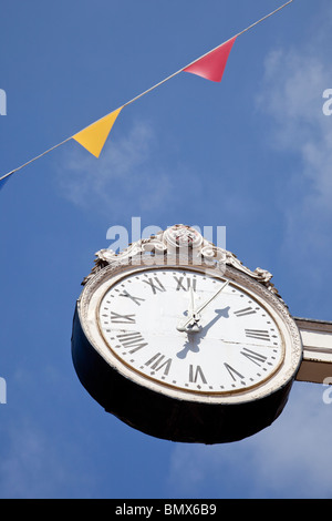 Uhr, 12:05, fünf Minuten nach zwölf mit blauem Himmelshintergrund und bunting Stockfoto