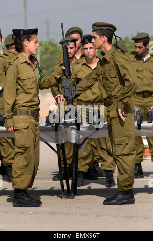 Eine israelische Polizistin Griffe M16 Gewehre zu IDF Rekruten während der Vereidigung Abschlussfeier in Nitzanim basic Infanterie Trainingslager in Israel. Stockfoto