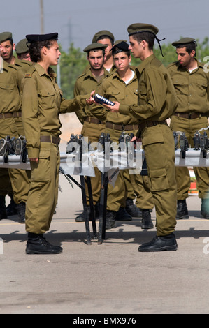 Eine israelische Beamtin nimmt IDF-Rekruten während der Vereidigung der Abschlussfeier im Basislager der Infanterie in Nitzanim in Israel Bibeln entgegen Stockfoto