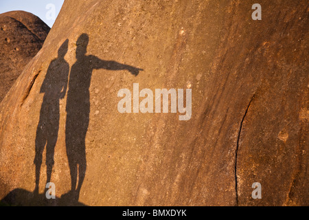 Schatten der beiden Bergsteiger auf einem Felsen in der warmen Abend Sonne im unteren Burbage, Peak District. Stockfoto