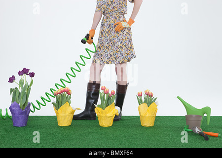 Frau mit Schlauch und Blumen auf Kunstrasen Stockfoto