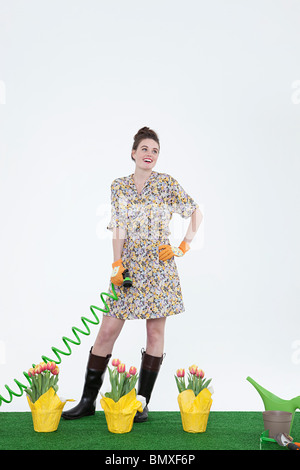 Frau mit Schlauch und Blumen auf Kunstrasen Stockfoto