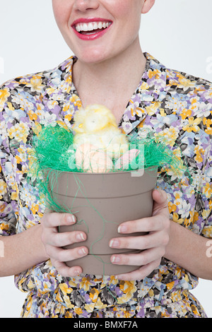 Junge Frau mit Osterküken und Eiern im Blumentopf Stockfoto