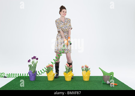 Frau mit Schlauch und Blumen auf Kunstrasen Stockfoto